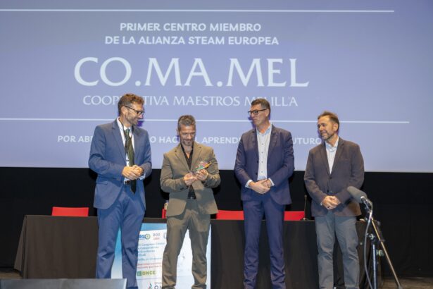 Cuatro hombres en un escenario junto a una pantalla con el logotipo de COMAMEL