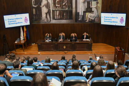 Auditorio con mesa y pantallas con el rótulo «Curso sobre la Carrera Investigadora»