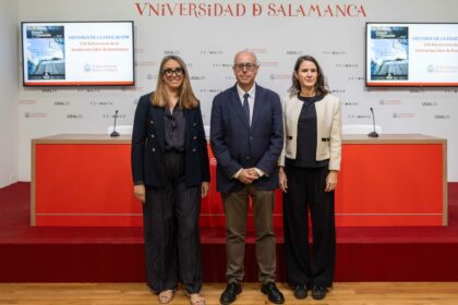 Tres personas posan en la presentación del monográfico de Historia de la Educación en la Universidad de Salamanca, con la portada de la revista en las pantallas