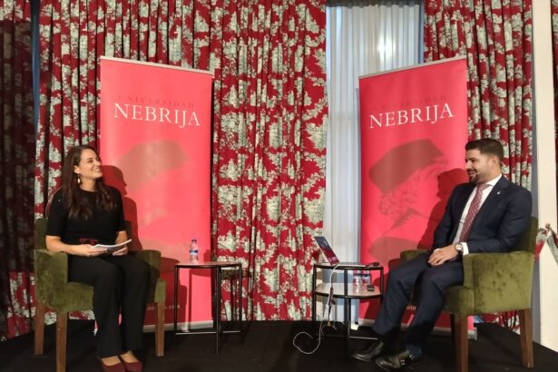 Dos personas sentadas ante paneles de la Universidad Nebrija