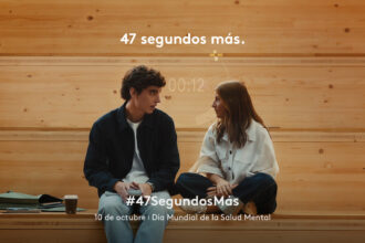 Dos jóvenes conversan sentados en un banco de madera en un fotograma de la campaña 47 segundos más