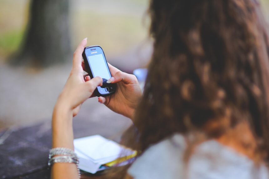 Una joven, de espaldas, escribe en un teléfono móvil