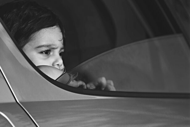 Primer plano en blanco y negro de un niño que mira con gesto serio por la ventanilla de un coche