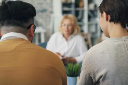 Dos personas de espaldas conversan con una profesional en una consulta