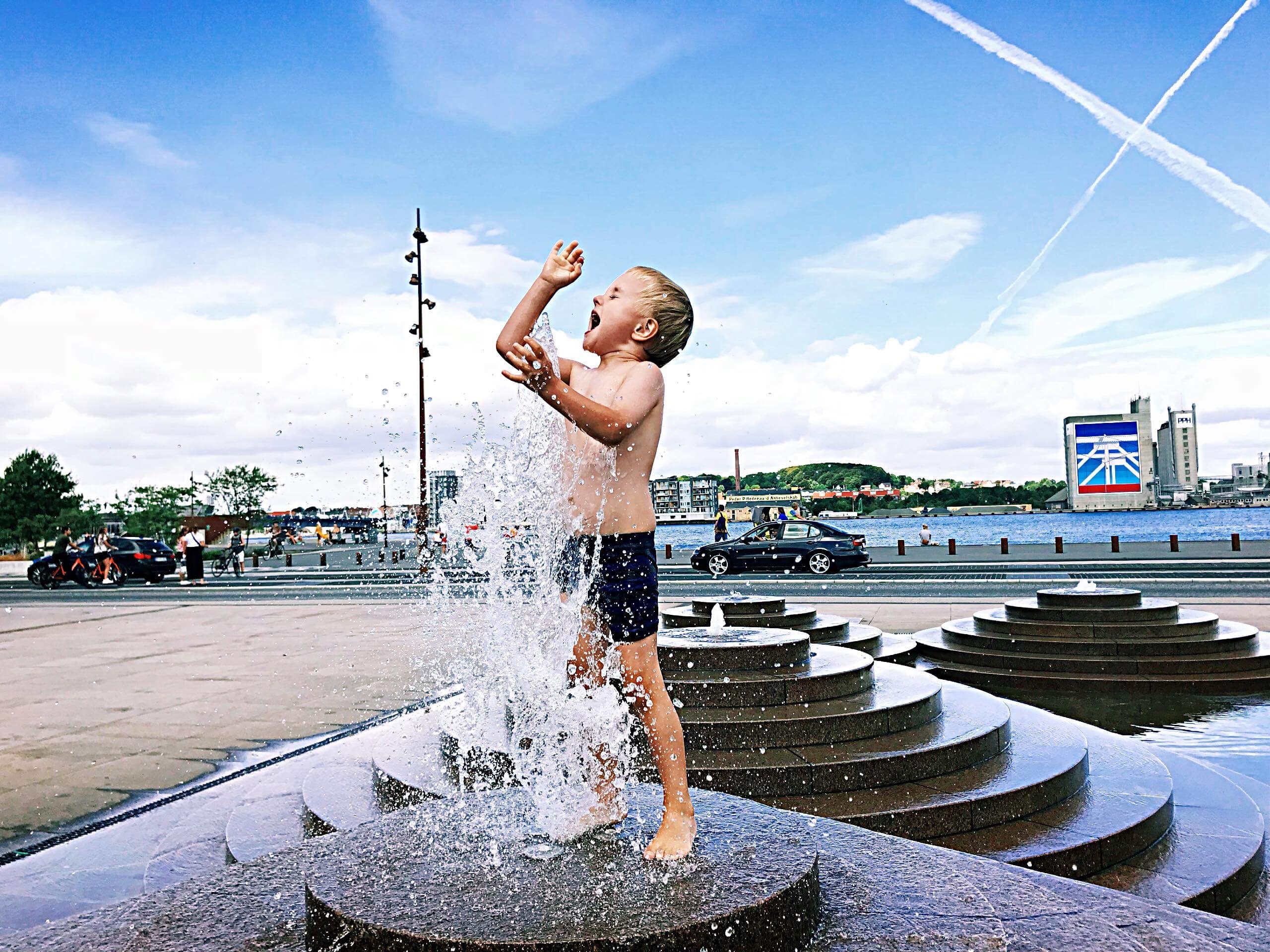 Un niño se refresca en una fuente